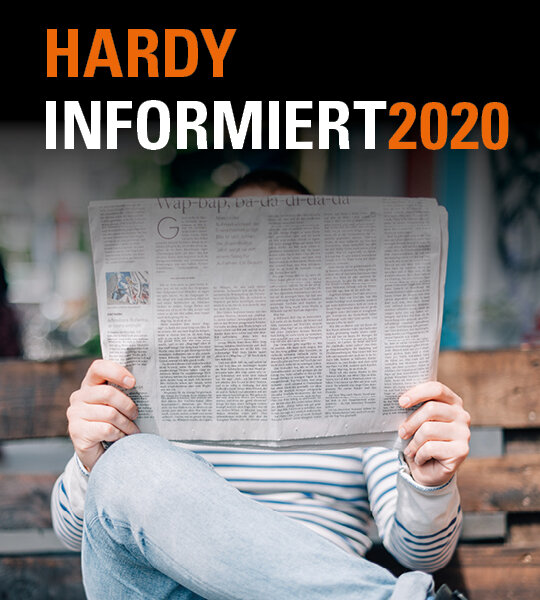 Person liest draußen Zeitung auf einer Bank