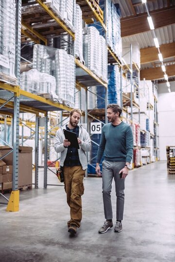 Elektrotechniker besichtigen im Lager vernetzte Beleuchtungslösung Interact Pro | © Signify GmbH