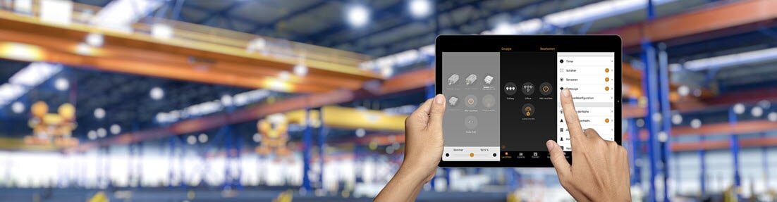 Smartphone mit Bedienungsapp vor industriellem Hintergrund.
