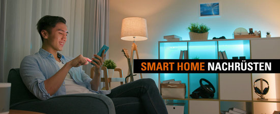 Ein junger Mann bedient sein nachgerüstetes Smart Home von der Smartphone-App aus.