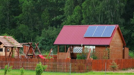 Gartenhaus mit Mini-Solaranlage und eingezäunten Garten mit Gartenspielgeräten. | © 2022 jarizPJ/Shutterstock