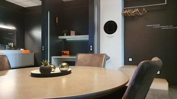 Lebensräume bei Hardy Schmitz Tisch mit Lederstühlen, Regale, Tablet zur Bedienung Smart Home in der Wand | © Hardy Schmitz GmbH
