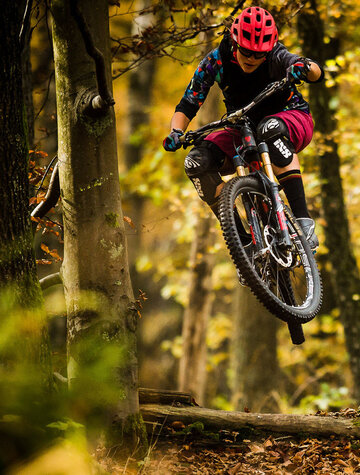 Steffi Marth auf Mountainbike im Wald. Mitten im Sprung.