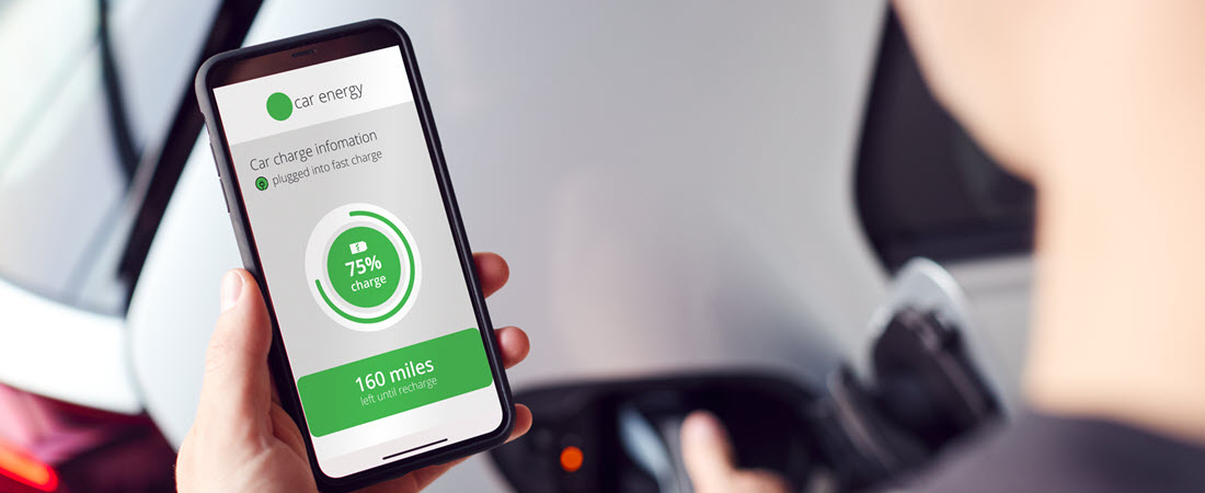 Person mit Smartphone in der Hand und einer App, welche gerade den Ladestand anzeigt und wie viel Kilometer damit noch gefahren werden könnten.